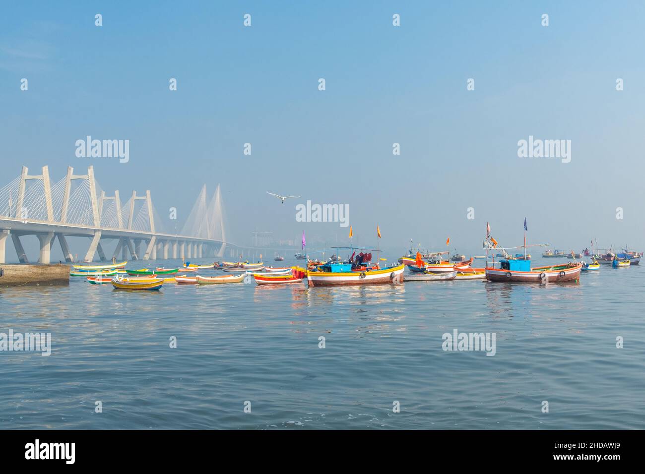 Pescatori tradizionali e colorati Barche di popolazione indigena accanto al moderno ponte 'Sea-link'. Mahim Bay, Mumbai, India. Foto Stock