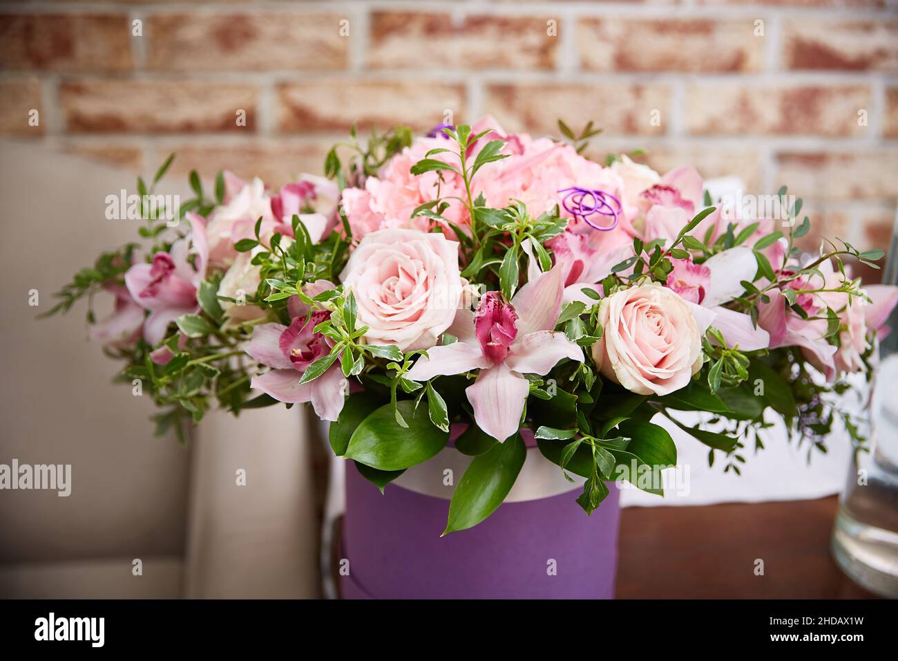 bouquet di rose rosa in una festosa scatola rotonda sul tavolo all'interno. Un regalo per una vacanza, un compleanno, un matrimonio, una Festa della mamma, un San Valentino, WOM Foto Stock