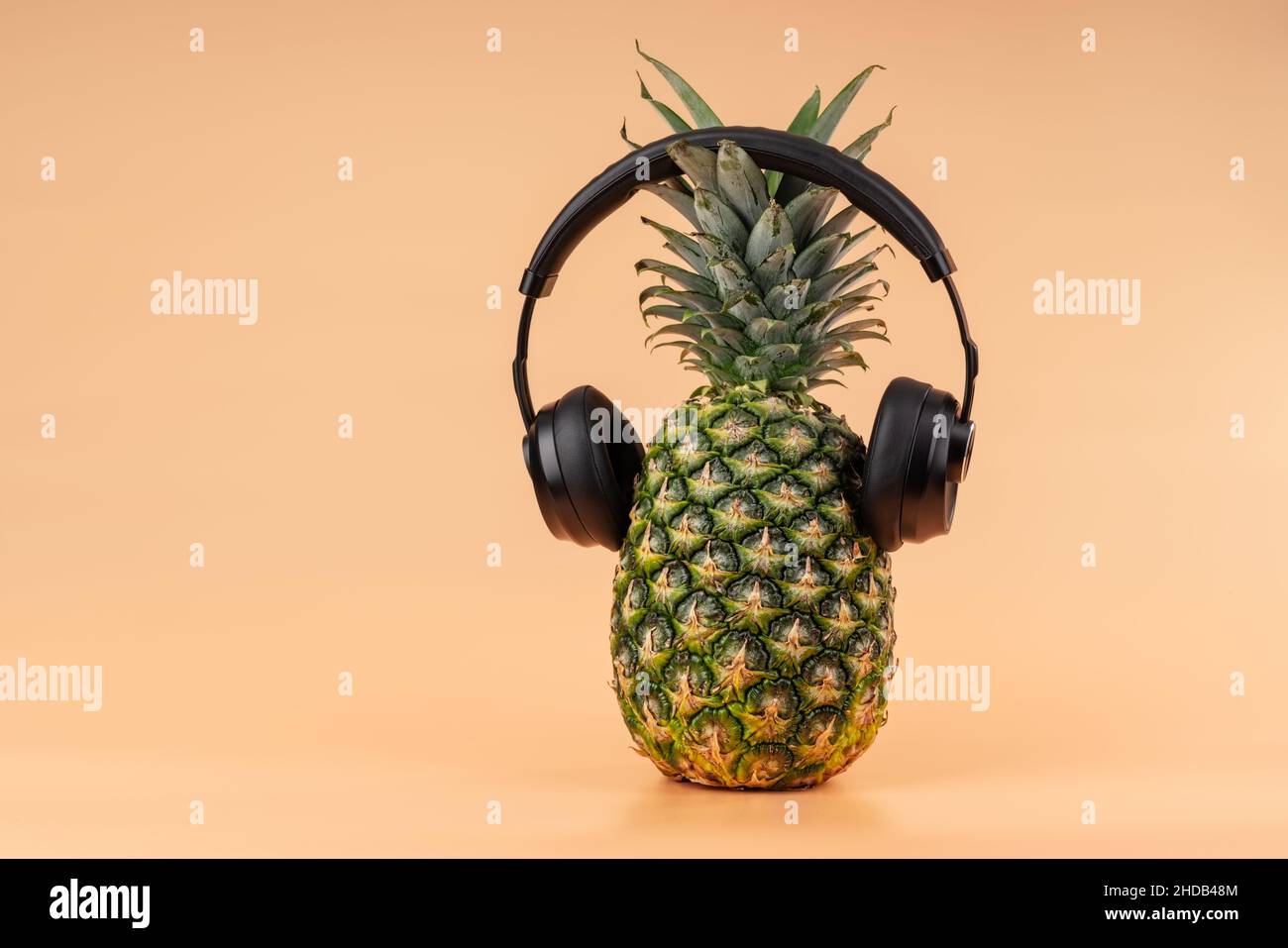 Interpretazione della frutta di ananas in un'immagine umana con cuffie per ascoltare musica concetto di relax e relax in vacanza. Foto Stock