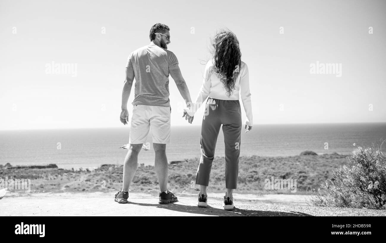 giovane coppia di famiglia che tiene le mani guardando l'acqua di mare dall'alto, libertà Foto Stock