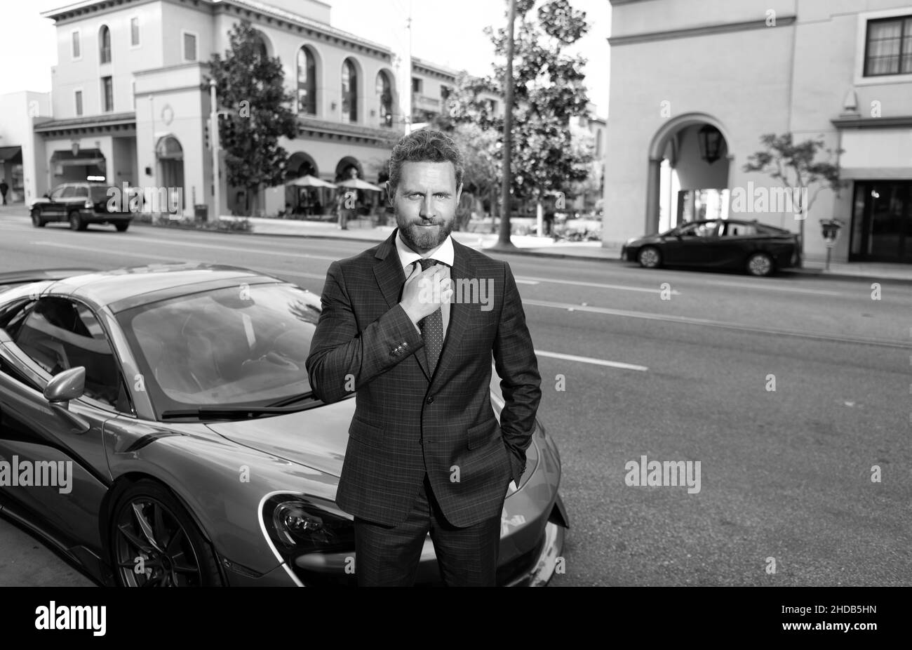 uomo d'affari sicuro in auto noleggio tuta in piedi all'aperto in strada, noleggio auto Foto Stock