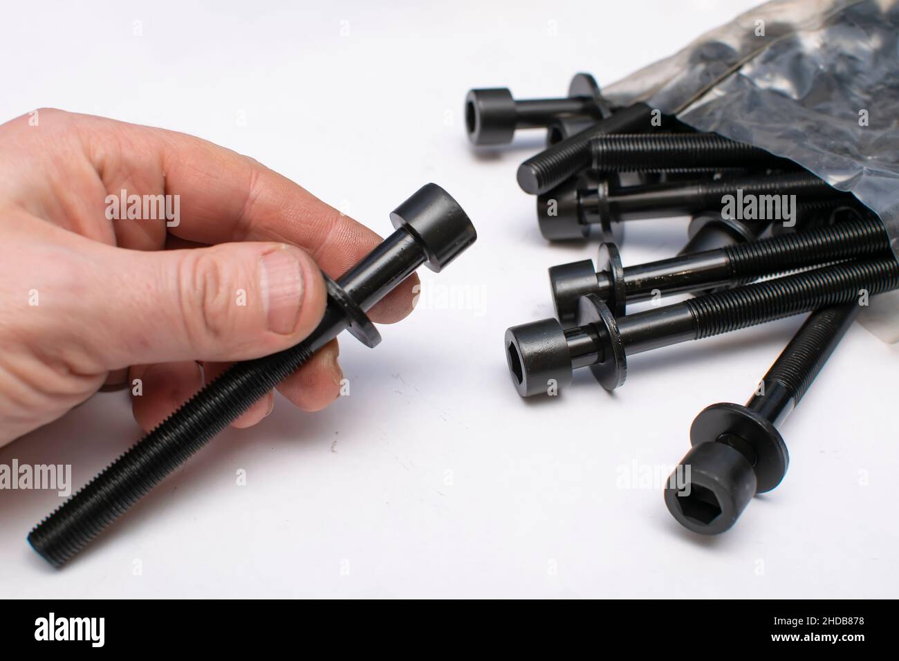 un bullone nero da un kit di riparazione auto in una mano uomo Foto Stock