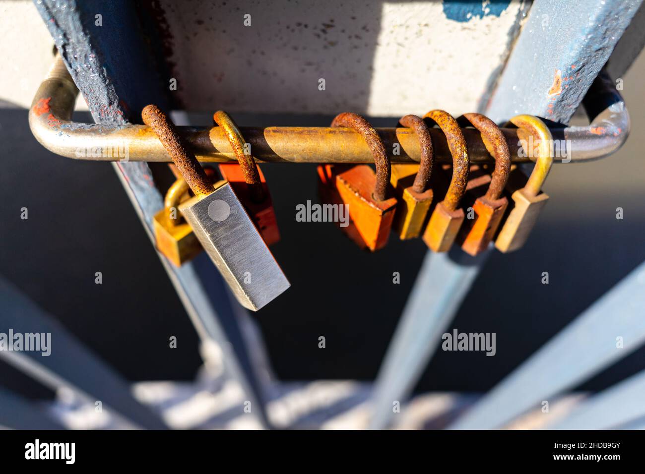 Vista angolata dall'alto sui lucchetti fissati alla ringhiera del ponte come simbolo dell'amore. Di giorno con messa a fuoco selettiva e sfondo sfocato. Foto Stock