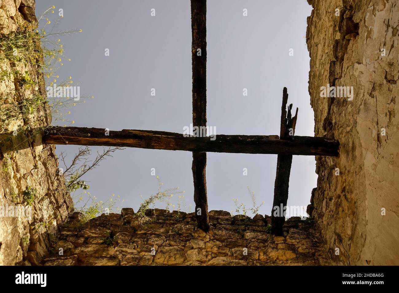Antica struttura in pietra con resti di travi in legno. L'erba cresce sulle pareti. Vista dal basso, contro il cielo blu. Spazio di copia. Messa a fuoco selettiva. Foto Stock