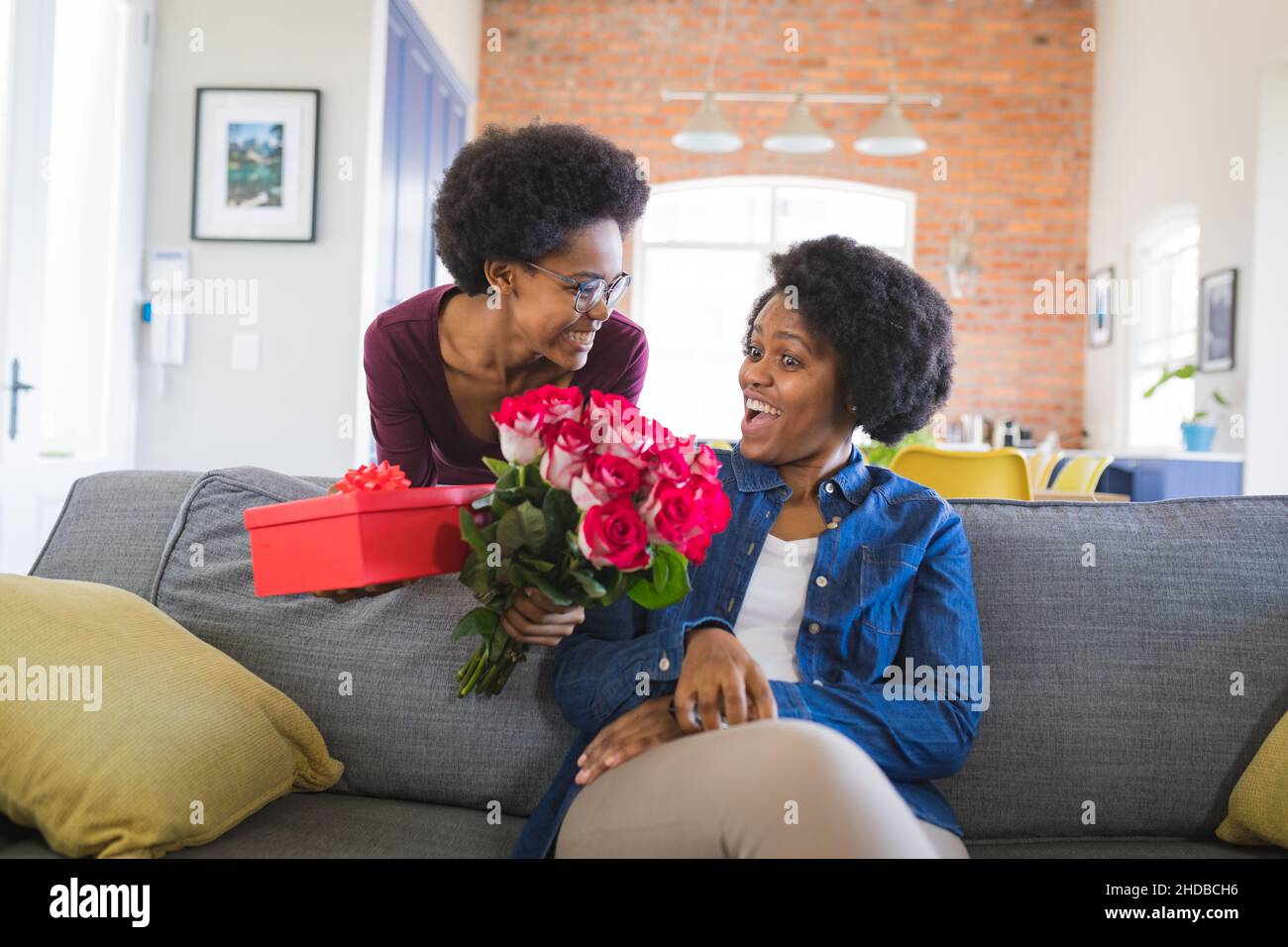 Sorpresa madre dalla figlia che dà il regalo e bouquet della rosa durante il compleanno nel paese Foto Stock