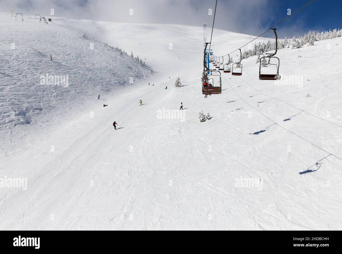 pista da sci da neve dall'altezza dell'ascensore. Stagione invernale, stazione sciistica, freddo tempo di neve soleggiato. Sciatori irriconoscibili scendendo la pista di uno sci r Foto Stock