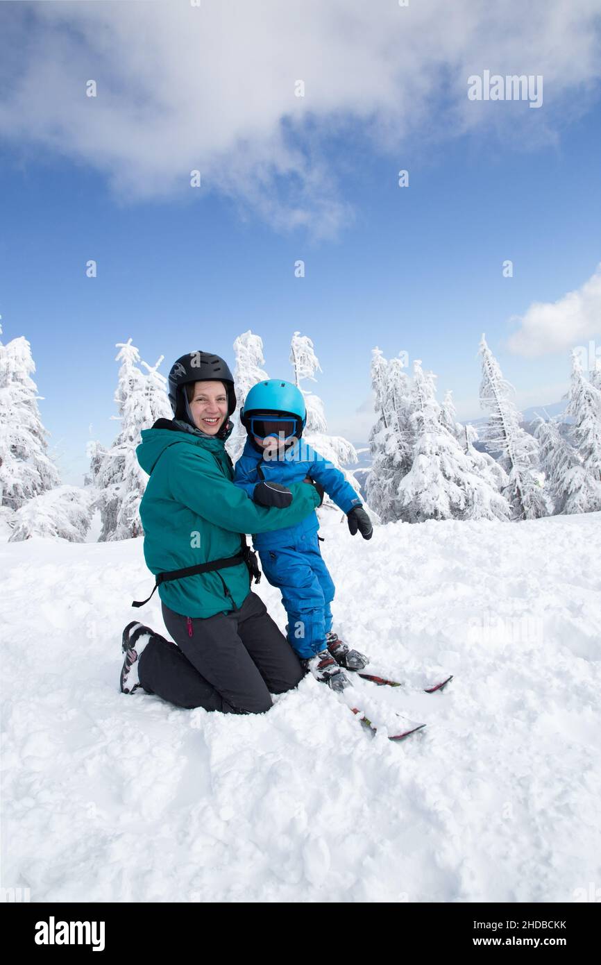 famiglia felice, mamma e bambino ragazzo in abiti caldi divertirsi all'aperto, imparare a sciare su una pista nevosa in una giornata fredda di sole in montagna. Godetevi la pinta Foto Stock