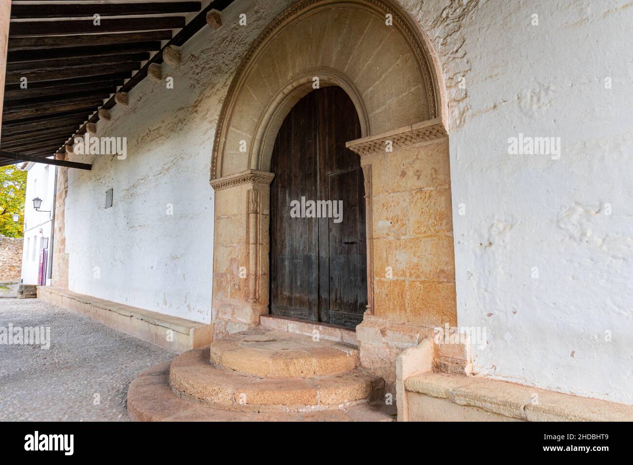 Fiancata di un muro di mattoni e ingresso con una porta di legno con un arco segmentale sotto il riparo Foto Stock