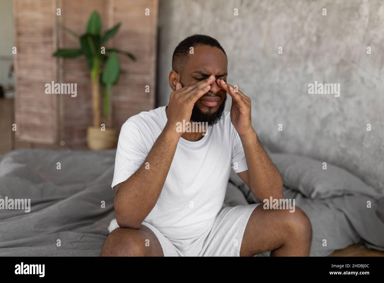 Uomo nero che soffre di mal di testa o di emicrania a letto Foto Stock