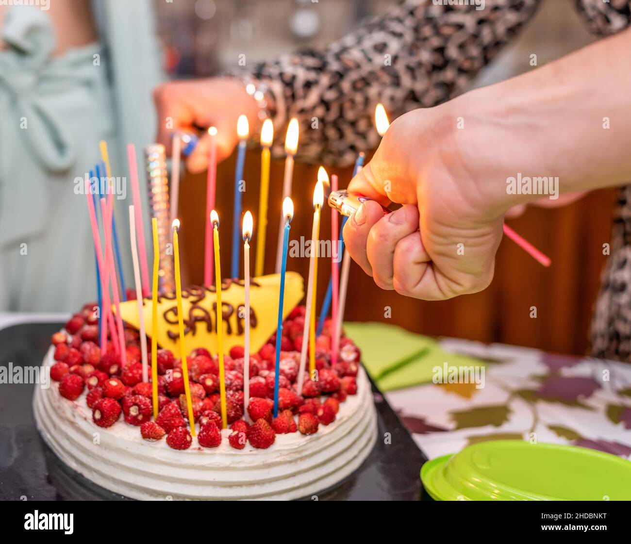 Torta di buon compleanno con candele colorate che bruciano e molte fragole rosse selvatiche Foto Stock