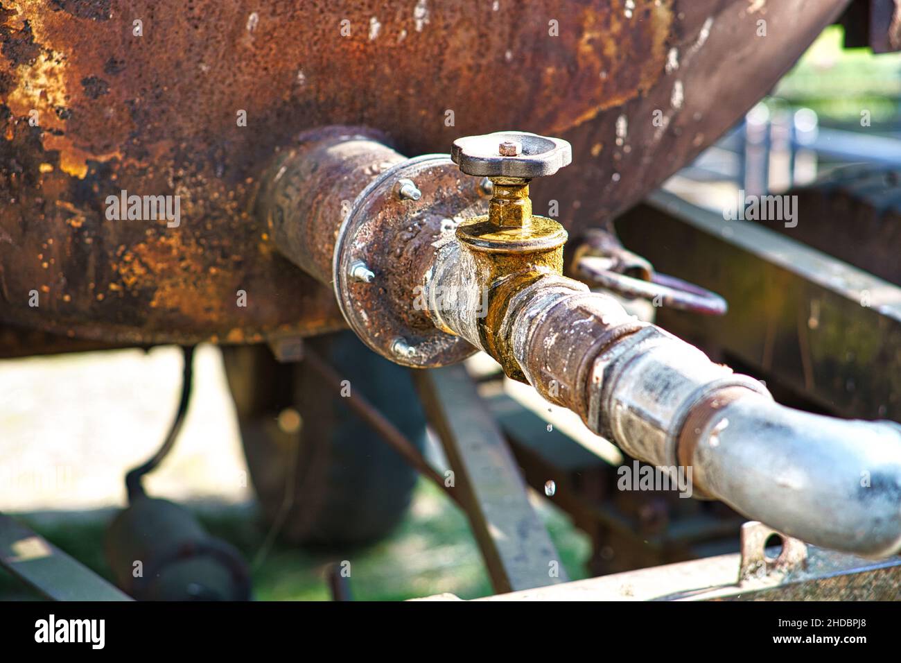 Rubinetto di gocciolamento di un serbatoio dell'acqua all'aperto . Le gocce cadono dal tubo. Ambiente rustico Foto Stock