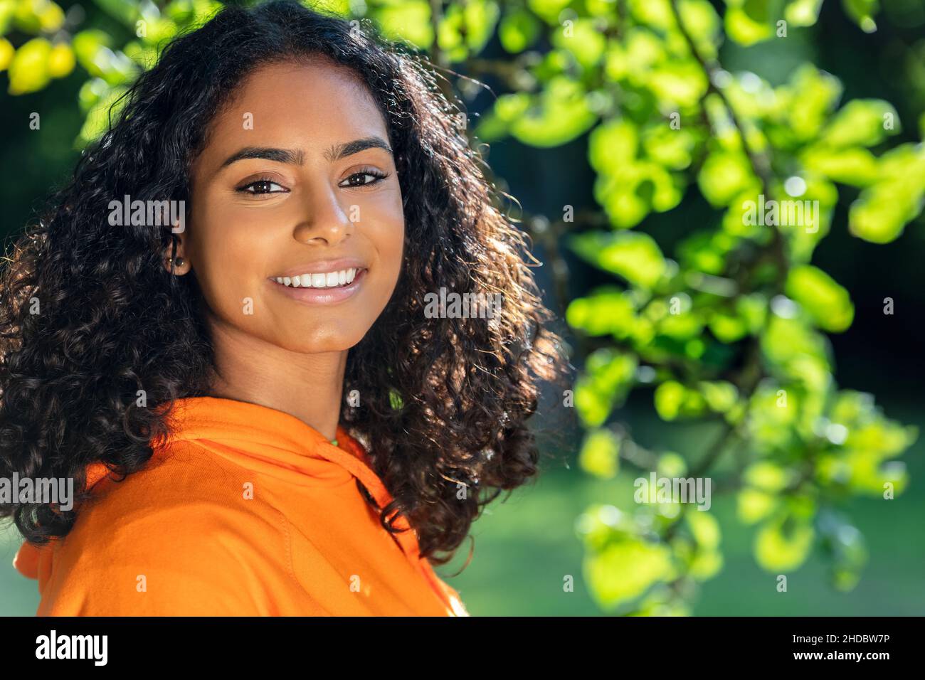 Ritratto esterno di bella corsa mista felice Africana americana ragazza adolescente femmina giovane donna che pensa e sorridendo con denti perfetti con una natura Foto Stock