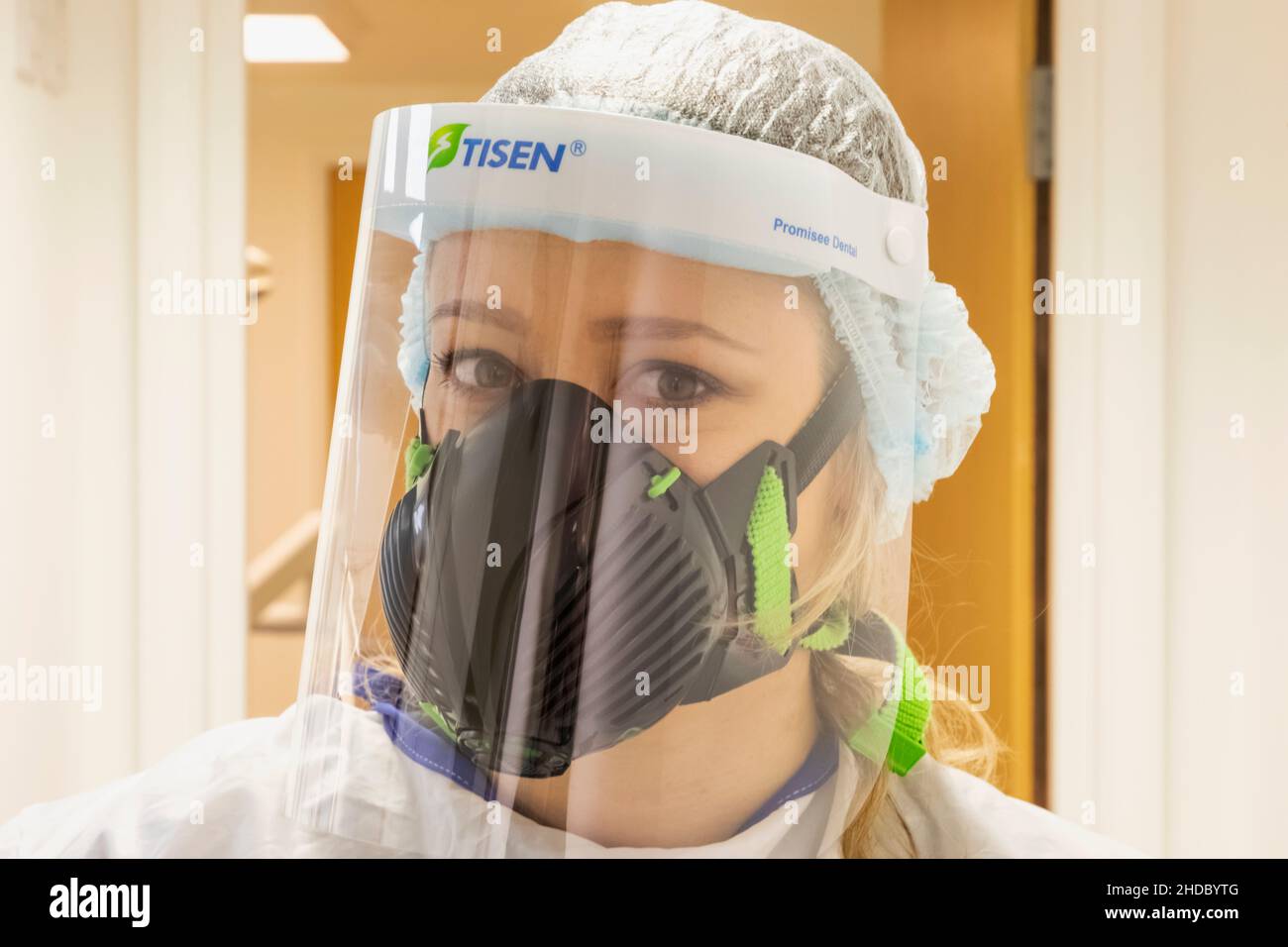 Inghilterra, Ritratto di un'infermiera femminile Pretty che indossa la maschera di protezione Covid PPE Foto Stock