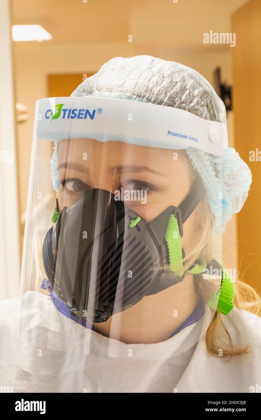 Inghilterra, Ritratto di un'infermiera femminile Pretty che indossa la maschera di protezione Covid PPE Foto Stock
