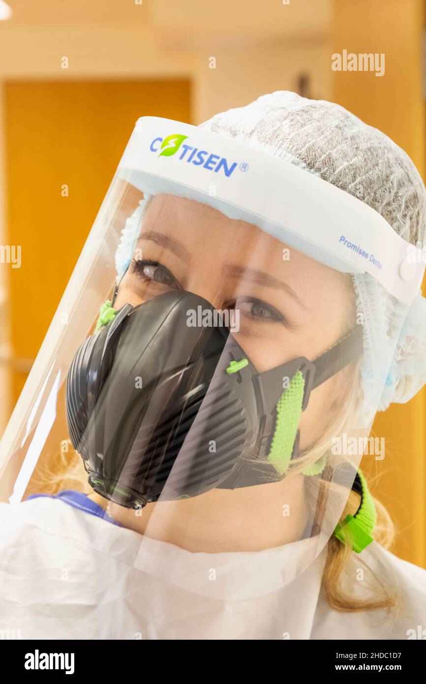 Inghilterra, Ritratto di un'infermiera femminile Pretty che indossa la maschera di protezione Covid PPE Foto Stock