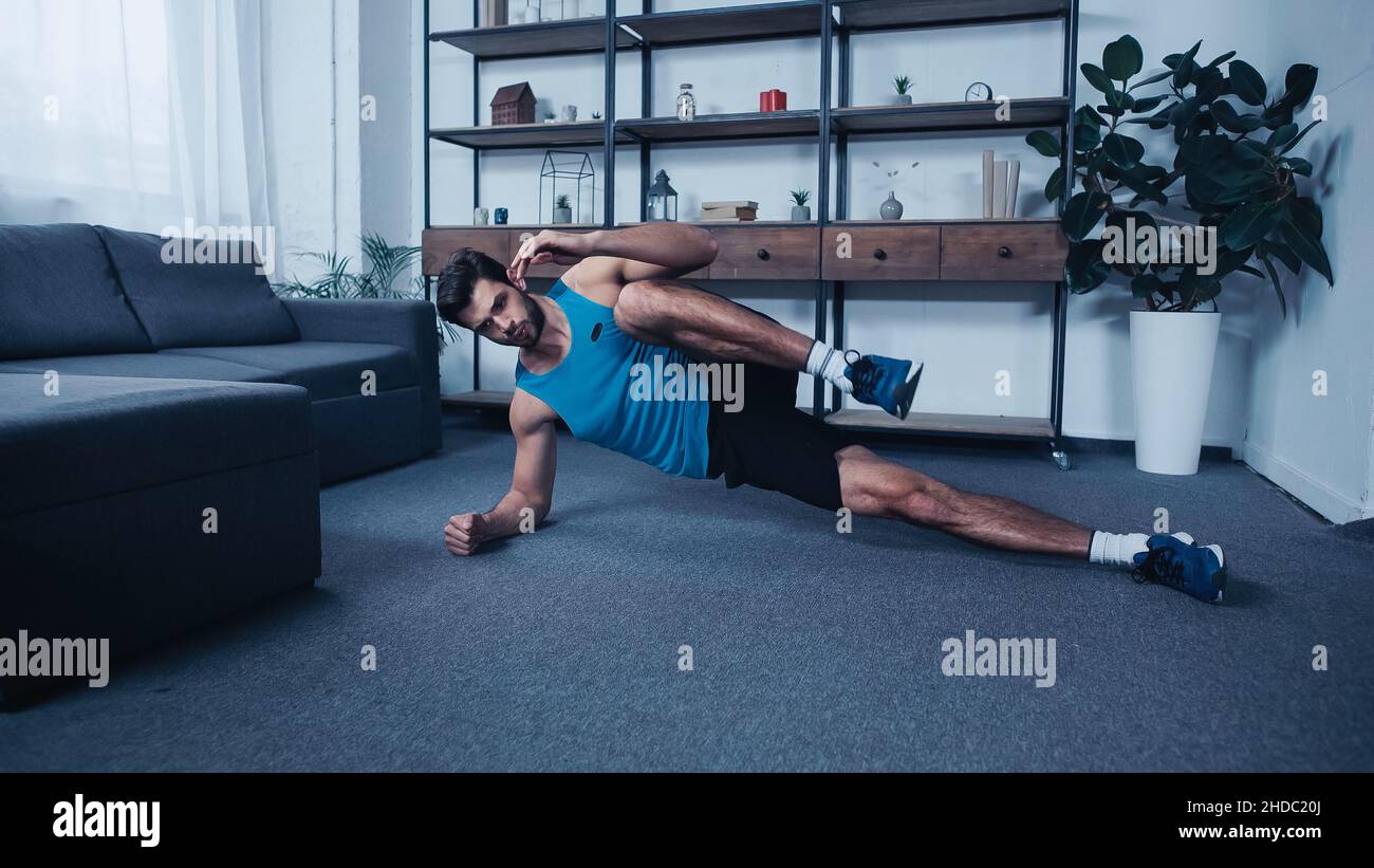 allenamento sportivo giovane e muscolare in posa a casa Foto Stock