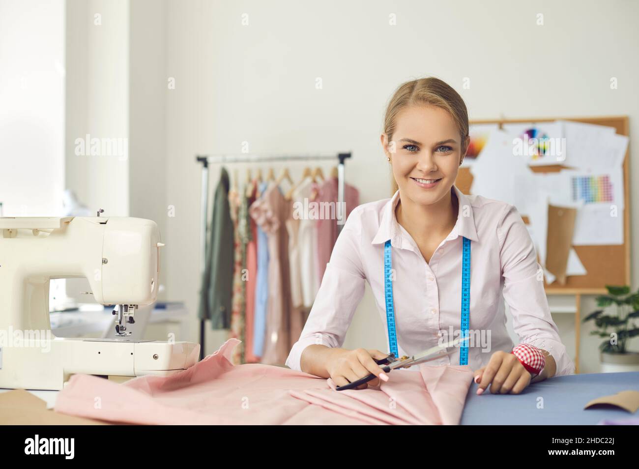 Ritratto di sorridente giovane marinaio femminile al suo posto di lavoro in studio di cucito. Foto Stock
