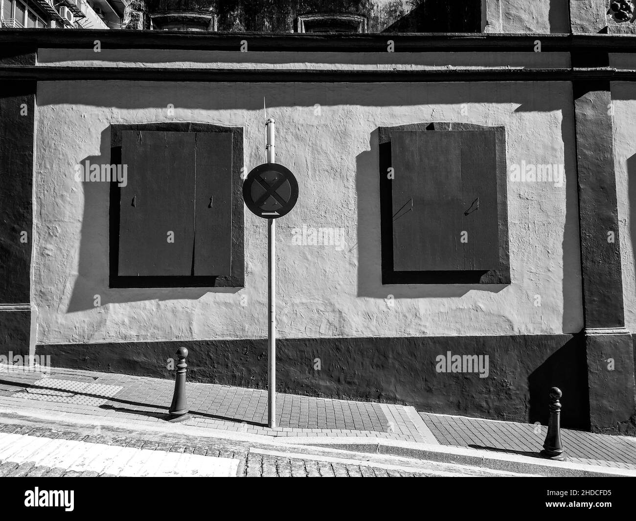 Scatto bianco e nero di un edificio con finestre di legno e un segnale di stop Foto Stock