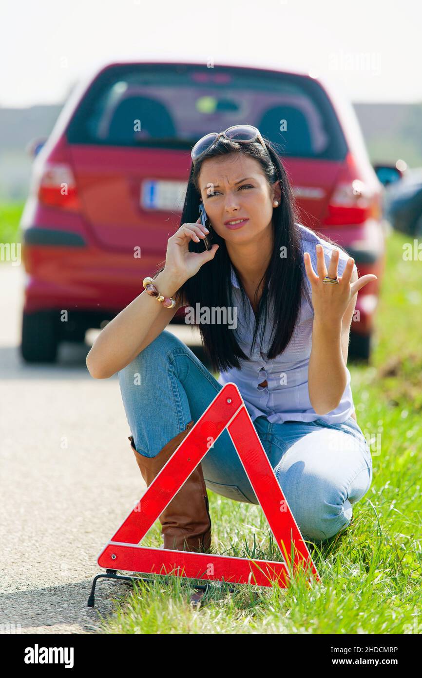 Junge Frau, 25, 30, Jahre, Mit einem Warndreieck bei einer Autopanne, signor: Sì Foto Stock