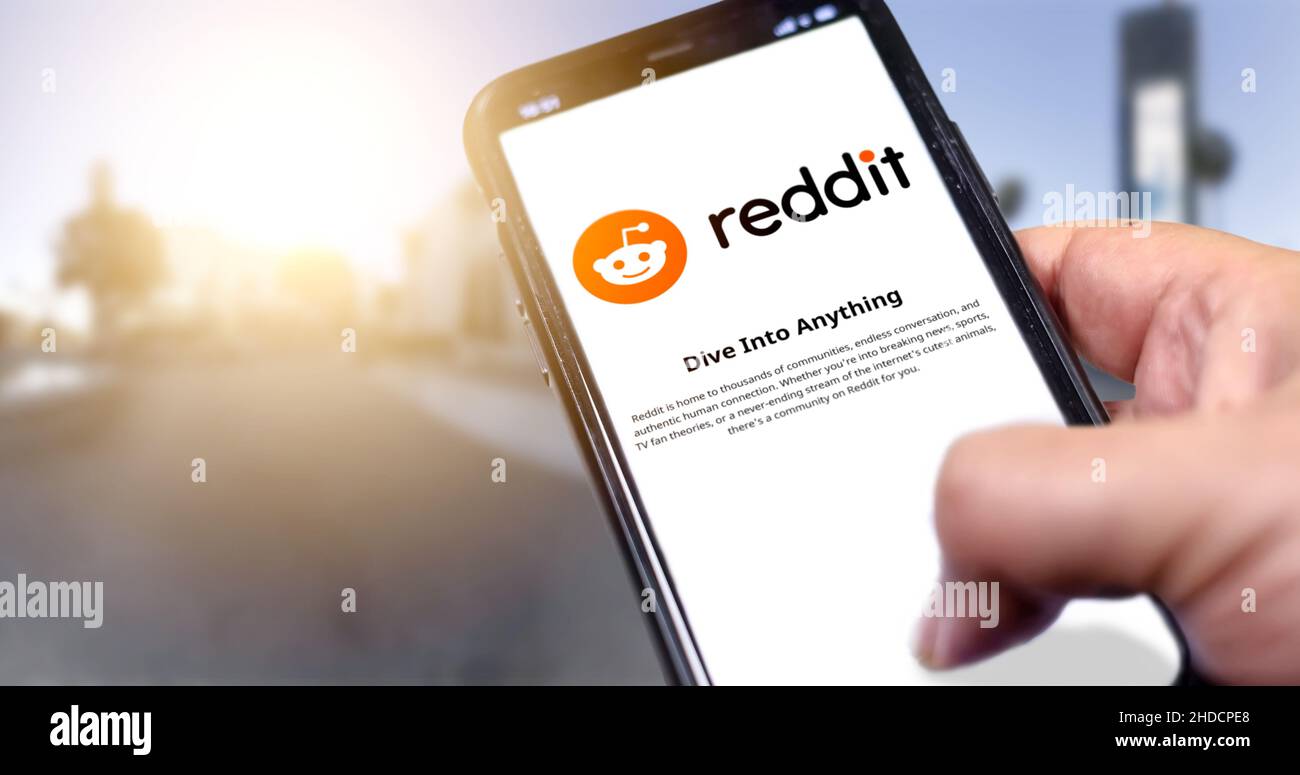 Roma, Italia, gennaio 2022: Tenere uno smartphone con l'app mobile Reddit sullo schermo su sfondo urbano. Reddit è una notizia sociale americana A. Foto Stock