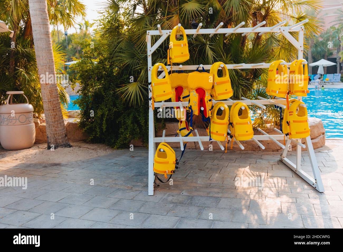 Stack di giubbotti di salvataggio gialli appesi su appendiabiti all'esterno durante le attività marine, abbigliamento di sicurezza, concetto di protezione. Foto Stock