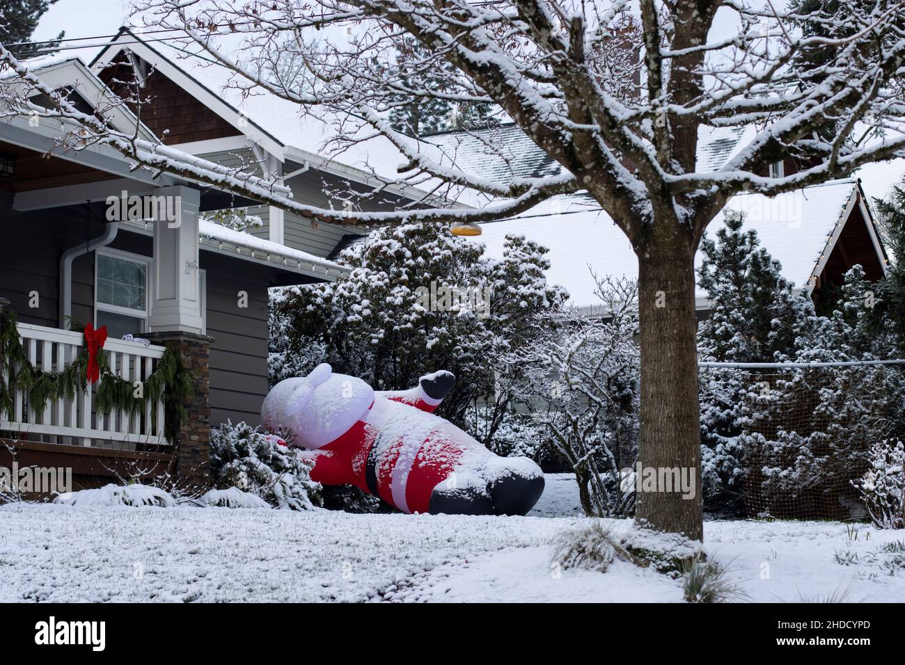 Santa gonfiabile cade nel cortile anteriore dopo notte alti venti e neve durante la stagione di festa invernale. Foto Stock