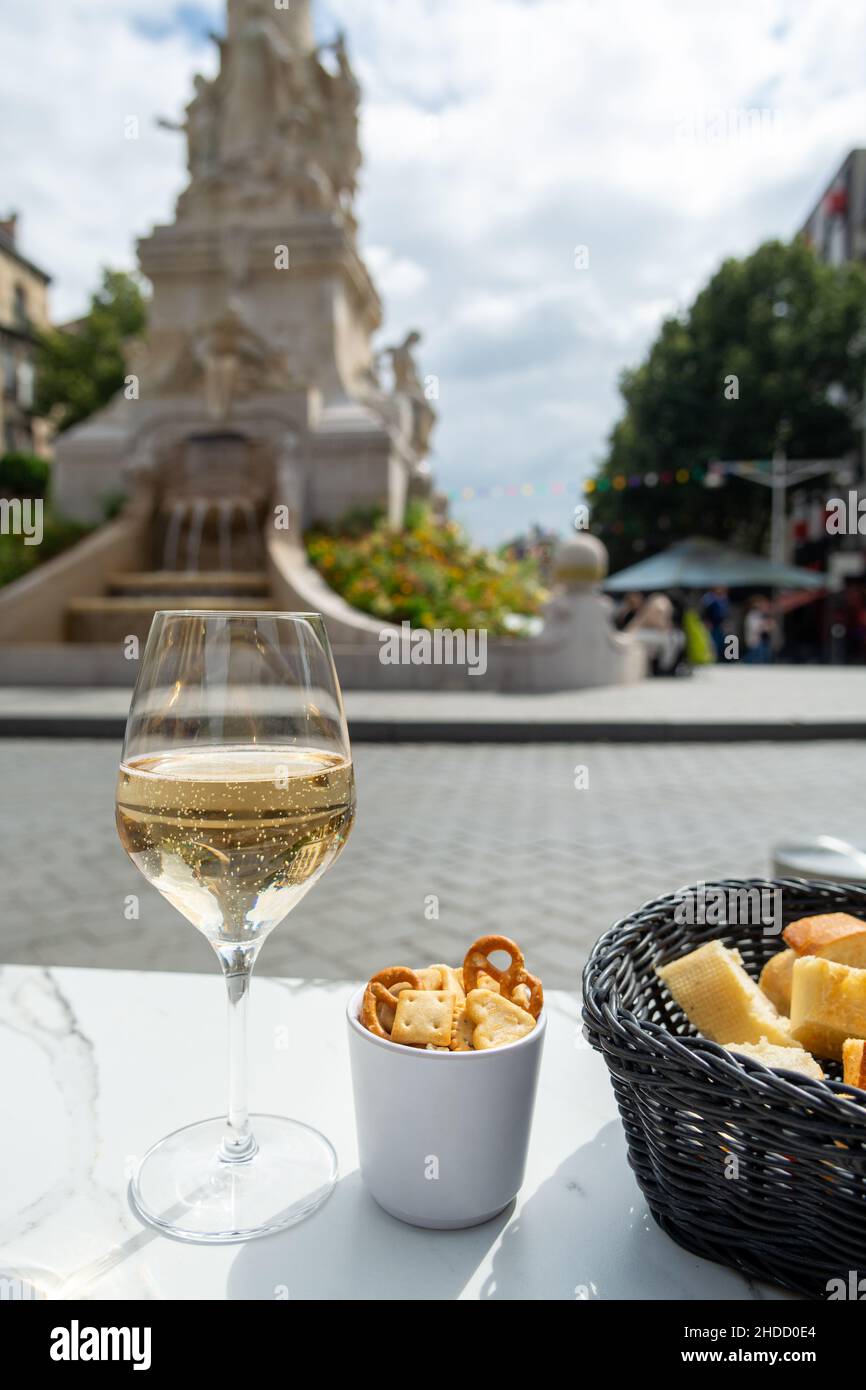 Bevendo di champagne brut frizzante vino in strada caffè con vista sulla parte vecchia centrale della città di Reims, Champagne, Francia Foto Stock