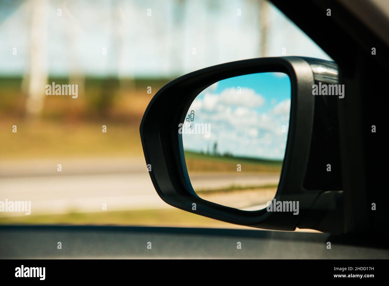 Un sensore di monitoraggio dei punti ciechi sullo specchietto retrovisore laterale di un'auto moderna. Foto Stock