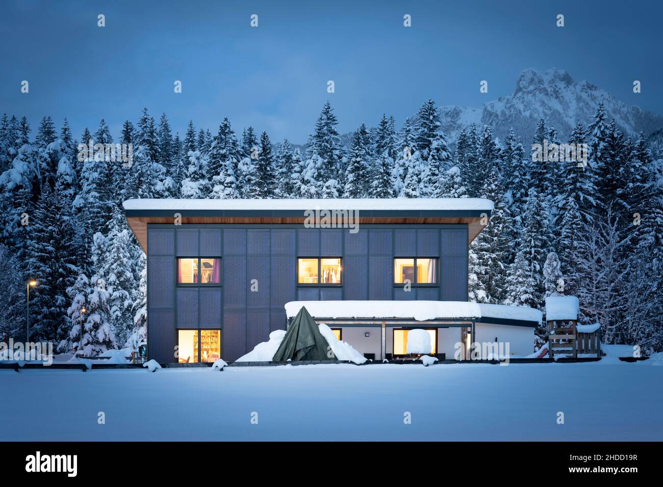 Vista frontale di una casa singola con facciata solare termale per riscaldamento sostenibile e rinnovabile e acqua calda di notte in inverno Foto Stock