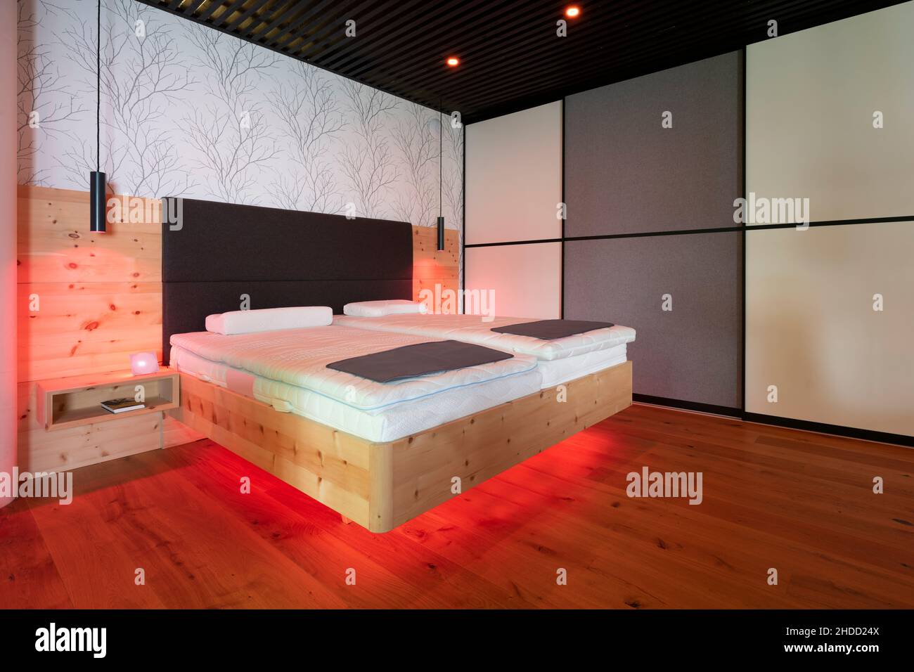 moderno letto in pietra di pino con illuminazione a led, lampade a sospensione e soffitto a doghe nero Foto Stock