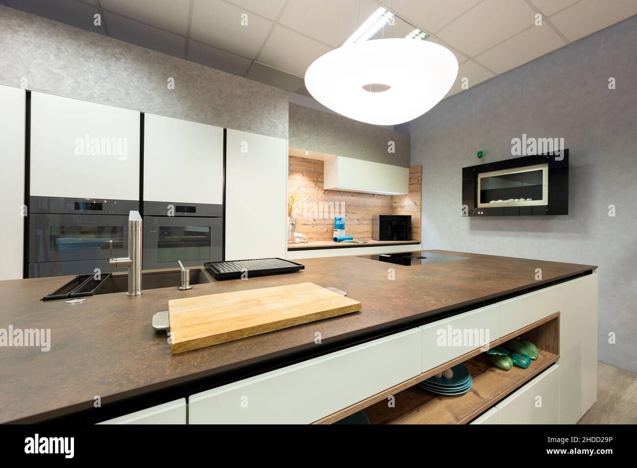 Vista della grande isola di cottura in pietra nella cucina moderna con alcova in legno e lampada di design a forma libera Foto Stock