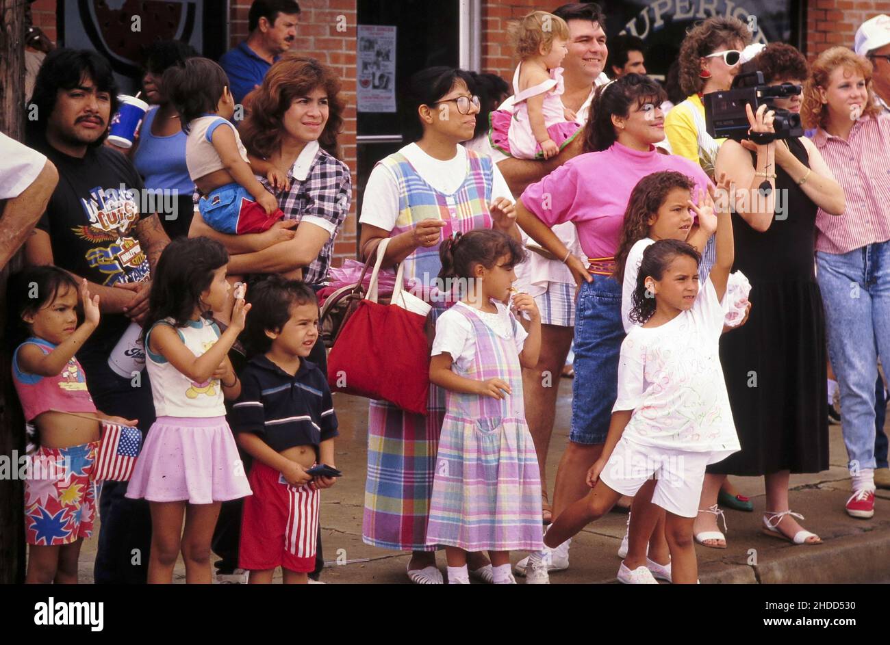 Luling Texas USA, 1990: Bambini e genitori si alzano sul marciapiede del centro mentre osservano la sfilata annuale di Luling Watermelon Thump. ©Bob Daemmrich Foto Stock