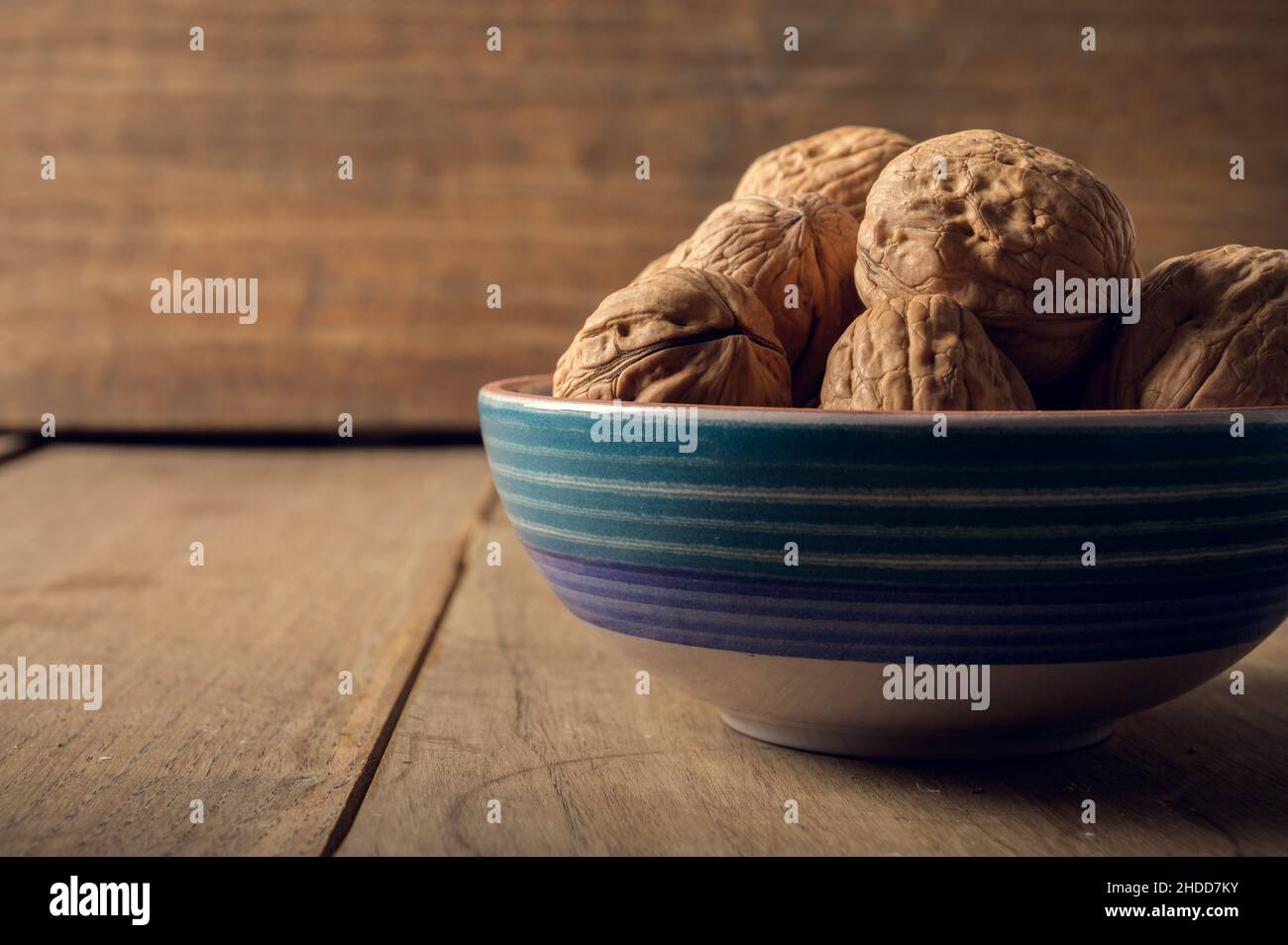 Noci in una ciotola di ceramica su sfondo di legno scuro Foto Stock