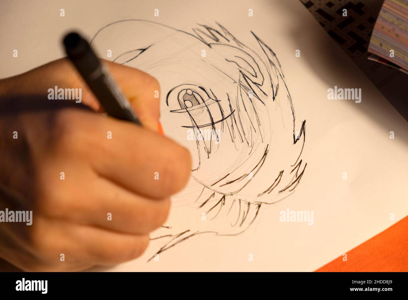 Mano della persona che tiene una penna nera che disegna un carattere giapponese del Manga su un foglio bianco di carta UK 2021 KATHY DEWITT Foto Stock