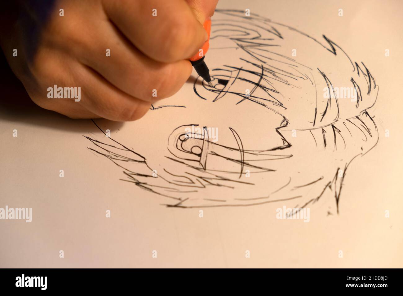 Mano della persona che tiene una penna nera che disegna un carattere giapponese del Manga su un foglio bianco di carta UK 2021 KATHY DEWITT Foto Stock