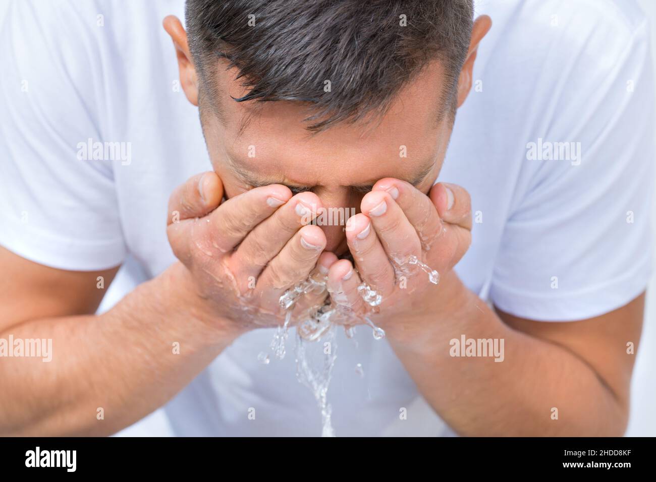 Ritratto di giovane uomo lavando viso con un tuffo d'acqua al mattino Foto Stock