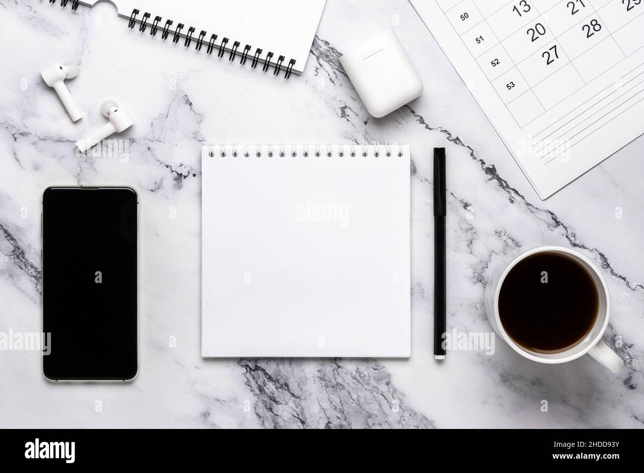 Tazza di caffè, telefono, cuffie, calendario e carta per notebook sul tavolo in marmo. Design piatto, concetto di pianificazione, impostazione degli obiettivi, stile monocromatico. Blac Foto Stock