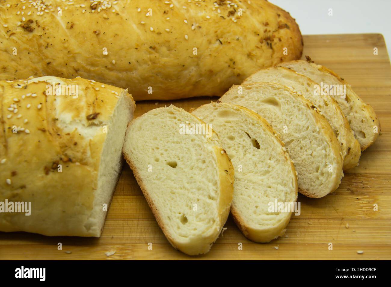 Pane di grano cotto dalla farina a casa. Pane affettato su tavola di legno sullo sfondo. Cibo SENZA OGM. Pane fatto in casa con spezie su di esso. Foto Stock