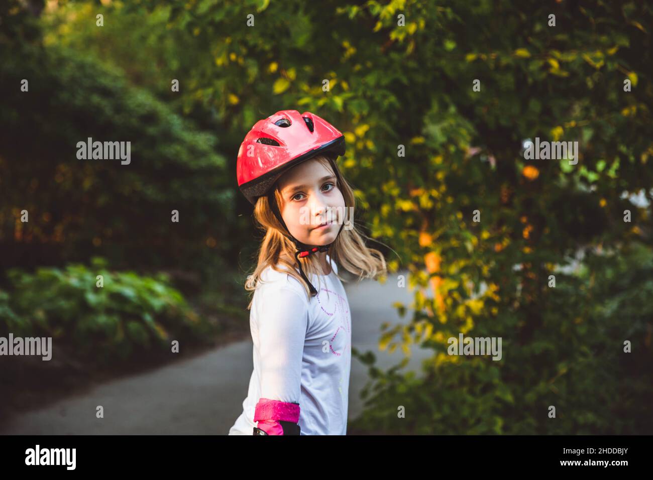 La bambina corre in runbike nel parco estivo. I bambini indossano le imbottiture di protezione e il casco di sicurezza per una guida sicura. Sport all'aperto per bambini. Estate spa Foto Stock