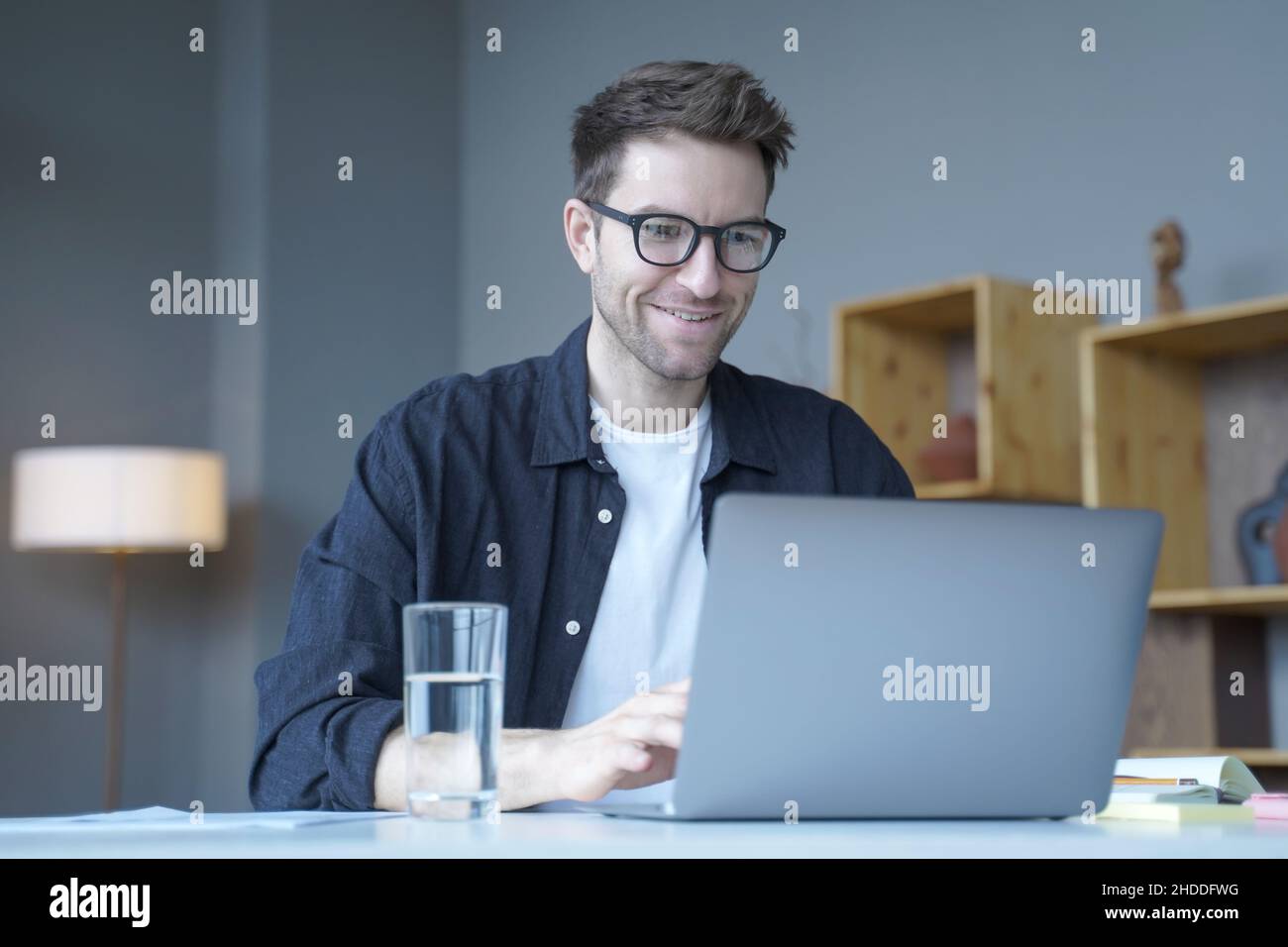 Giovane uomo d'affari sorridente consulente finanziario europeo che lavora in remoto online da casa Foto Stock