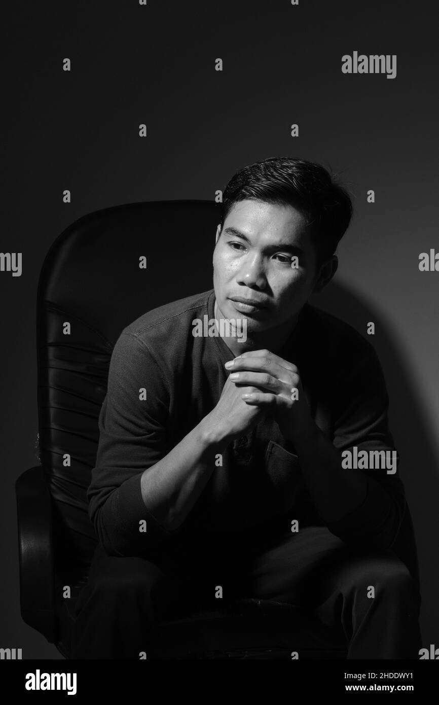 L'uomo moderno seduto su una sedia e di stile moderno nello studio, bianco e nero Foto Stock