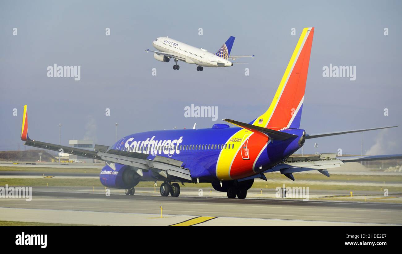 Southwest Airlines Boeing 737 taxi sulla pista dopo l'atterraggio all'aeroporto internazionale o'Hare di Chicago, mentre un aereo Unito decollera in lontananza. Foto Stock