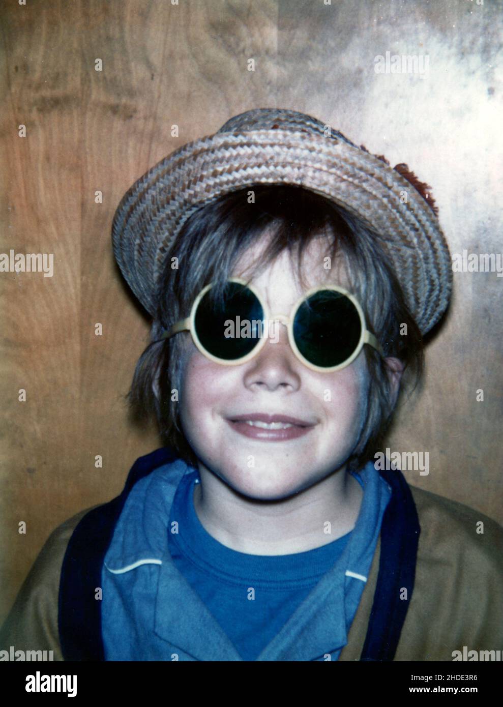 Un ragazzo in posa con un cappello di paglia e occhiali da sole funky, circa 1970 Foto Stock