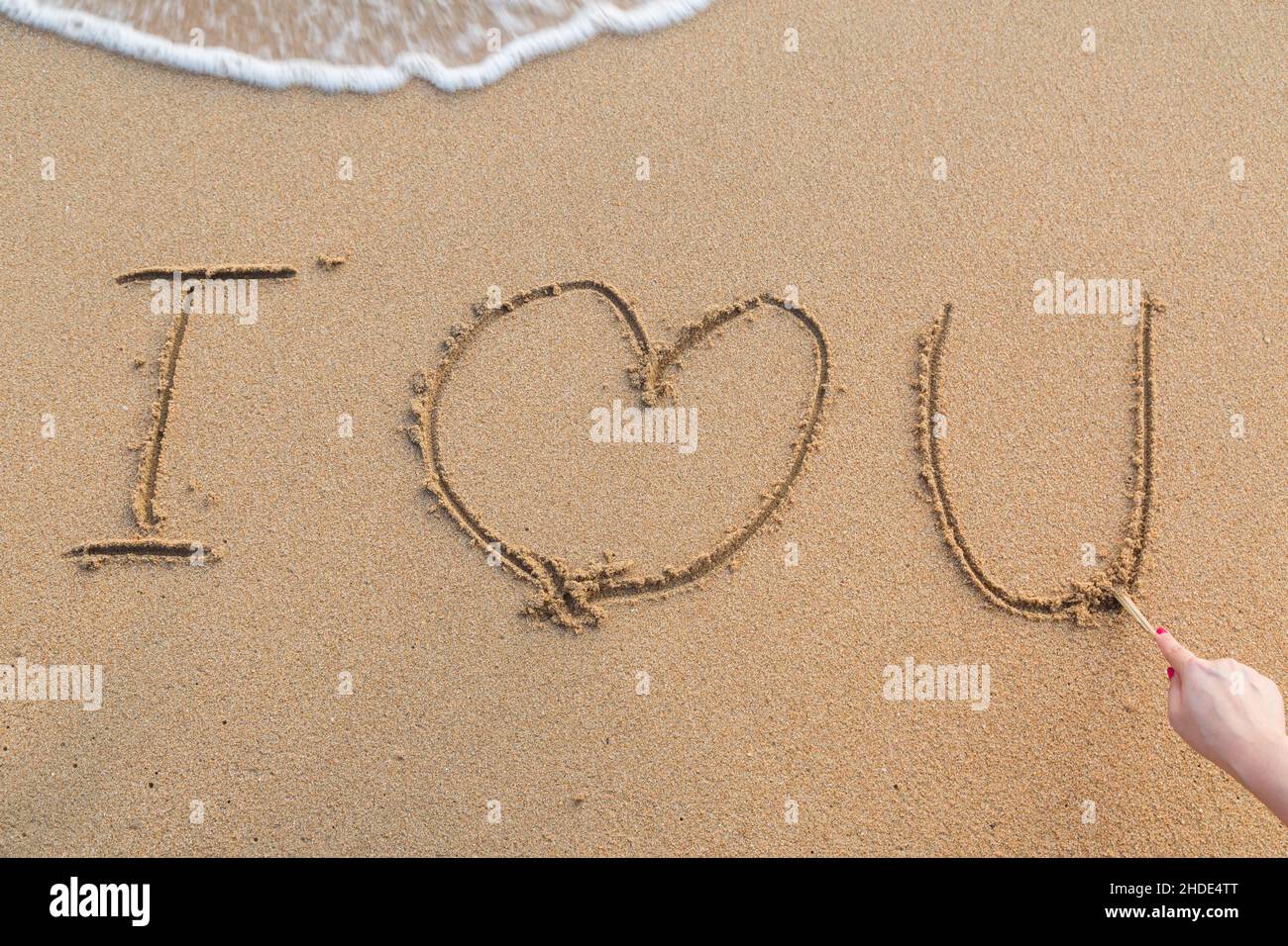 Messaggio ti amo sulla sabbia con la donna del disegno a mano sulla spiaggia Foto Stock