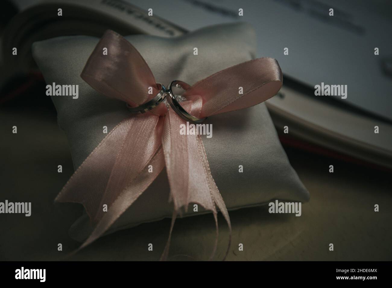 Primo piano di anelli di nozze su un piccolo cuscino con nastro rosa Foto Stock