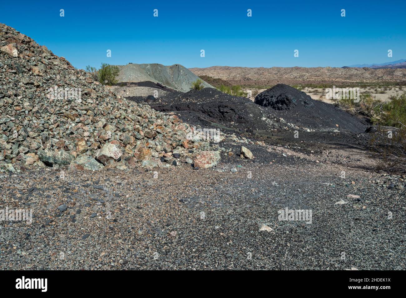 Rifiuti di roccia (grigio), scorie (nero) residui di scarto vicino fonderia di rame a Swansea miniera di rame Townsite, Buckskin Mountains, Sonoran Desert, Arizona, Stati Uniti Foto Stock