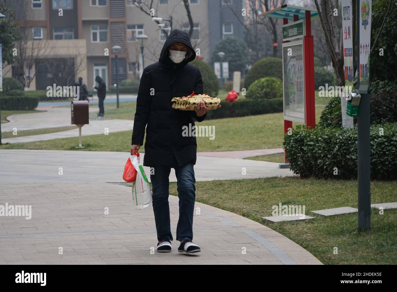 XI'AN, CINA - 6 GENNAIO 2022 - i residenti trasportano le forniture per andare a casa in una comunità chiusa a Xi'an, provincia di Shaanxi, Cina, 6 gennaio 2022. Foto Stock