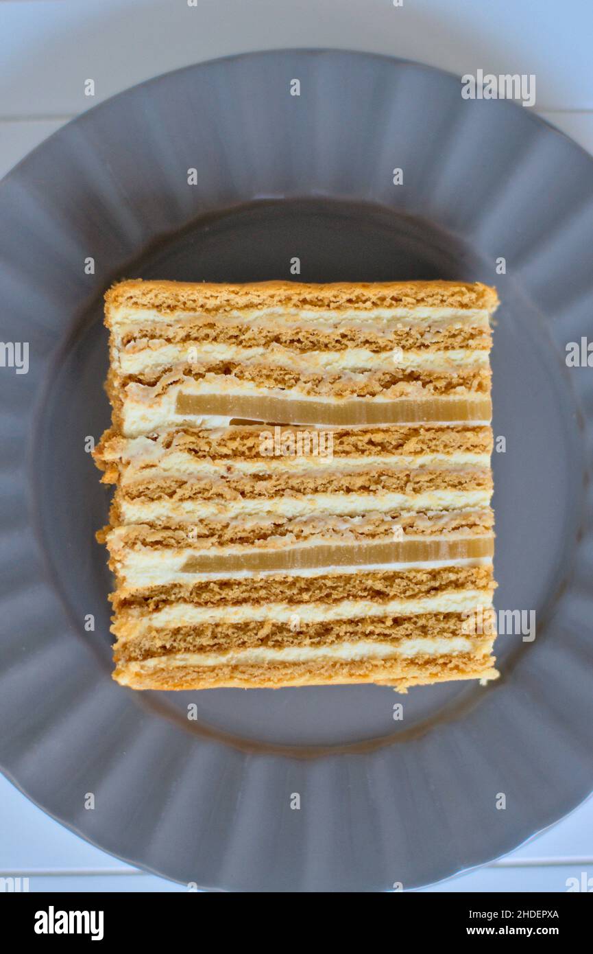 Pezzo di torta al miele con due strati di marmellata di pere su piatto grigio Foto Stock