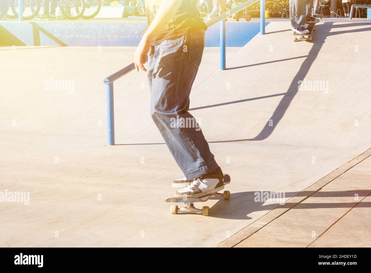 Skater ragazzo skateboard alla rampa di skatepark nella soleggiata giornata estiva in città. Vita urbana attiva. Sottocultura urbana. Foto Stock