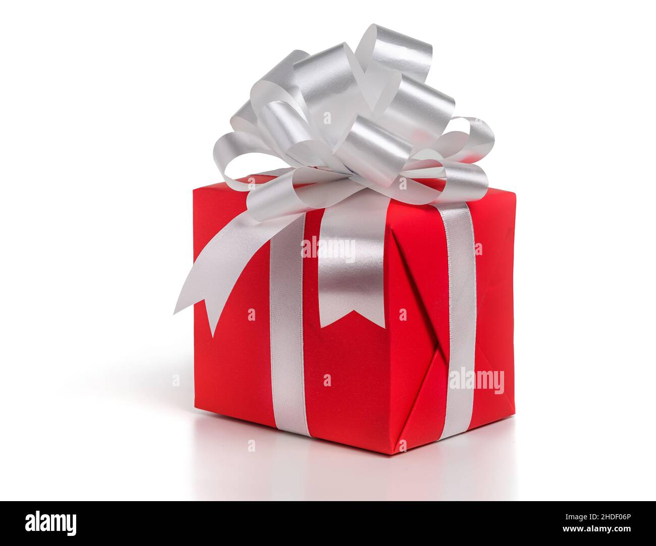 Confezione regalo avvolta in carta rossa con arco in argento su sfondo bianco. Foto Stock